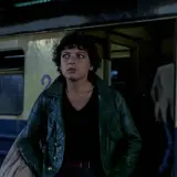 Młoda kobieta w zielonej kurtce stoi przy pociągu. To scena z jednego z filmów Barbary Sass.