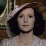 Elegancka Elżbieta, aktorka w kapeluszu i perłach, pozuje na tle obrazu.