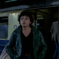 Młoda kobieta w zielonej kurtce stoi przy pociągu. To scena z jednego z filmów Barbary Sass.