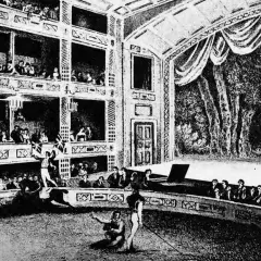 Widownia wypełnia wielopoziomowe loże, a na arenie trwa spektakl. To scena z życia teatru średniowiecznego, pełna widzów i aktorów.