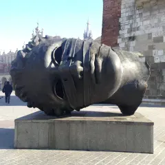 Gigantyczna, metalowa głowa, dzieło polskiego rzeźbiarza, leży na cokole na krakowskim Rynku.
