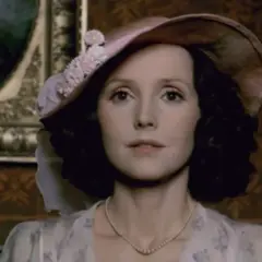 Elegancka Elżbieta, aktorka w kapeluszu i perłach, pozuje na tle obrazu.