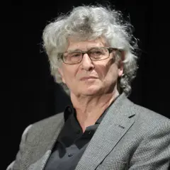 Portret starszego mężczyzny z siwymi włosami i okularami, w marynarce. Może to być Feliks Falk, twórca niezapomnianych filmów.