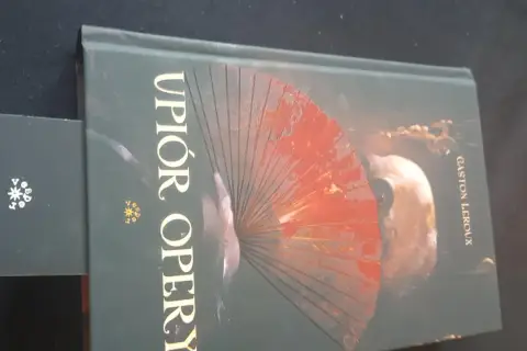 Okładka książki "Upiór w operze" z wachlarzem i maską.