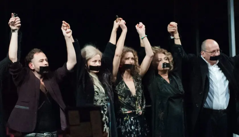 Aktorzy Teatru Polskiego we Wrocławiu z zakrytymi ustami, podnoszą ręce w geście protestu.