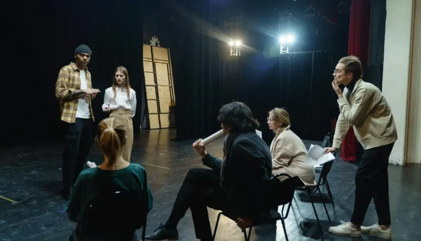 Aktorzy i reżyser dyskutują na scenie, przygotowując się do spektaklu.