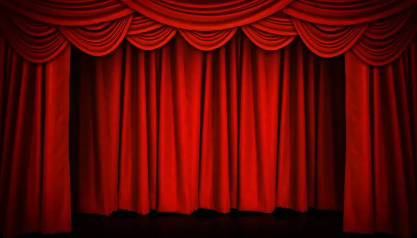 Czerwona, teatralna kurtyna w teatrze, z bogatymi drapowaniami u góry, gotowa do odsłonięcia sceny.