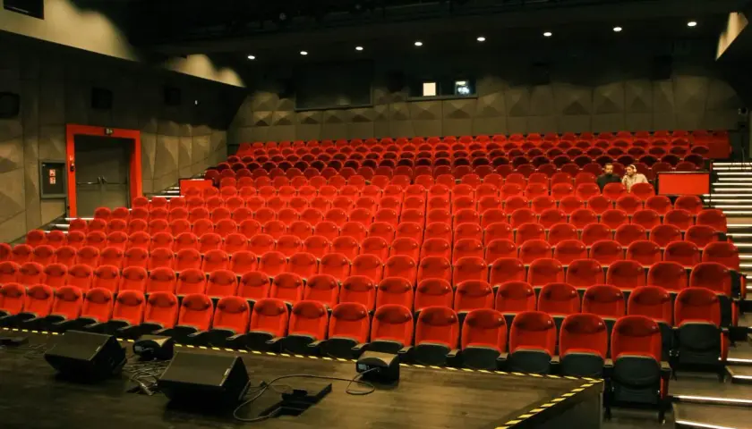 Widok na puste czerwone fotele w sali kinowej lub teatralnej.