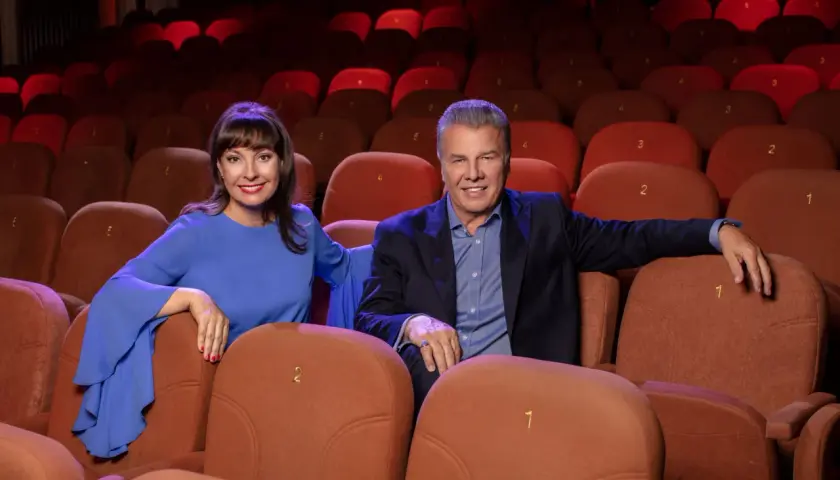 Uśmiechnięci aktorzy w Teatrze Kamienica, siedzący w rzędzie pomarańczowych foteli.