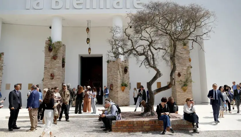 Ludzie spacerują przed budynkiem z napisem "la Biennale". Atmosfera jak na Biennale Wenecja 2026.