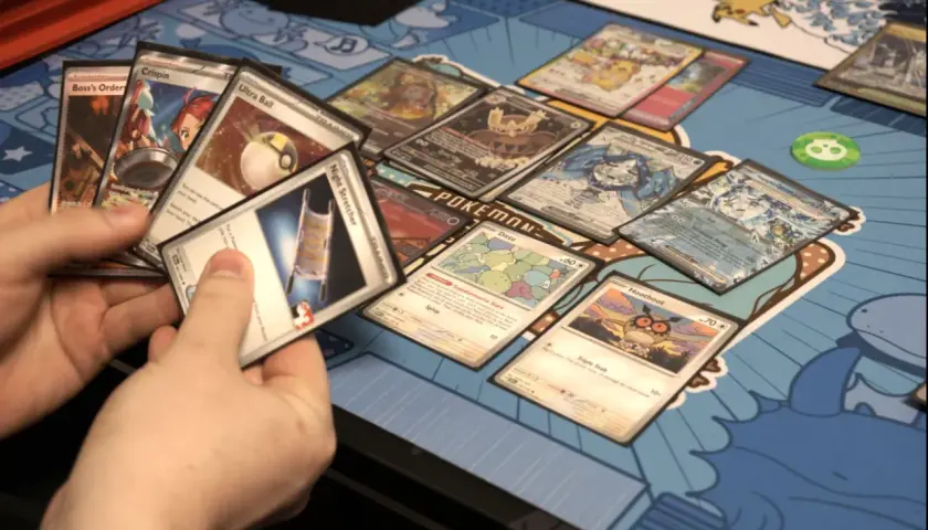 Gracz wybiera karty do gry, na stole leżą kolorowe karty Pokémon.