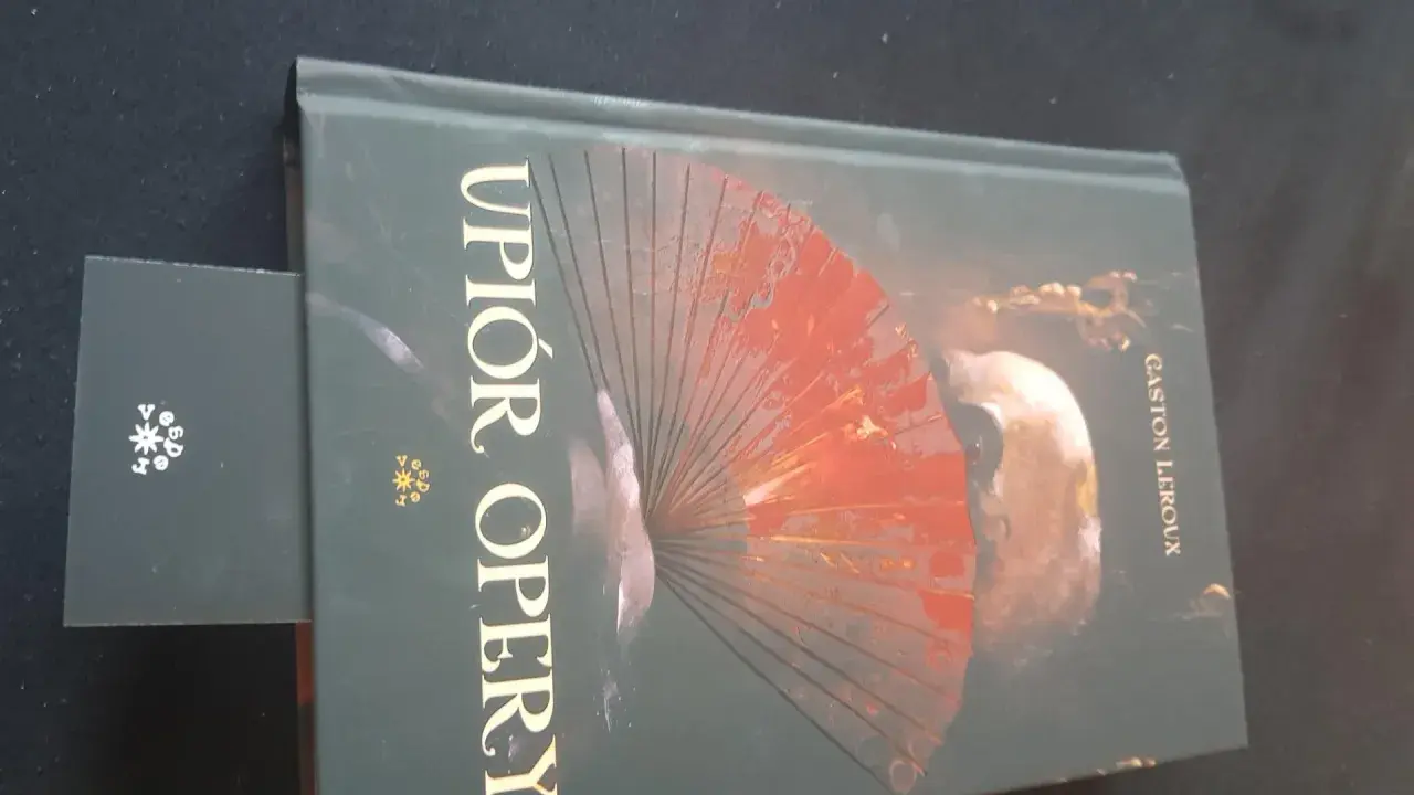 Okładka książki "Upiór w operze" z wachlarzem i maską.