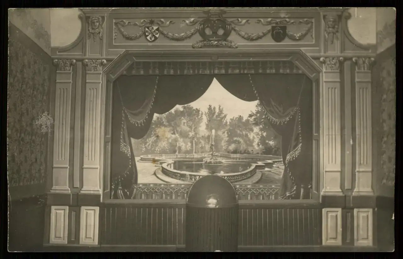 Zasłona w teatrze odsłania malowniczy ogród z fontanną.